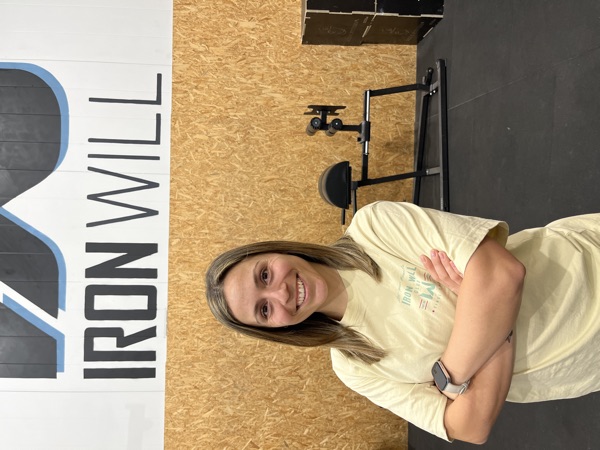 Meri, coach de Pilates en Iron Will Box, con el logo del box de fondo